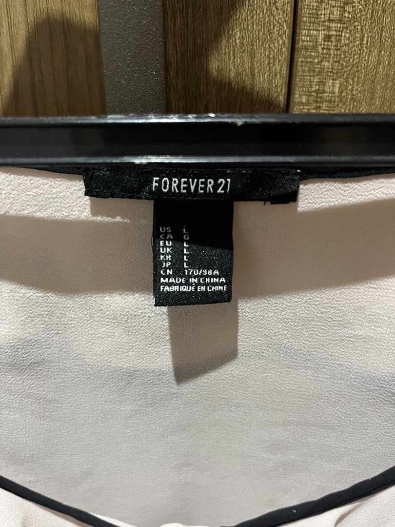 Forever 21 Ruffle Collar Blouse Size L (Category: Blouses) located in Quezon City. Submitted by epictiger.c6451a (Listing ID 1465963760, Image 3). Description: - Brand: Forever 21 - Size: L (tag attached) - Color: Light pink with black trim - Design: Double ruffle collar, button-up front, long sleeves with trimmed cuffs - Material: Lightweight fabric - Origin: Made in China - Condition: Excellent/Ready to wear - Versatility: Perfect for both work