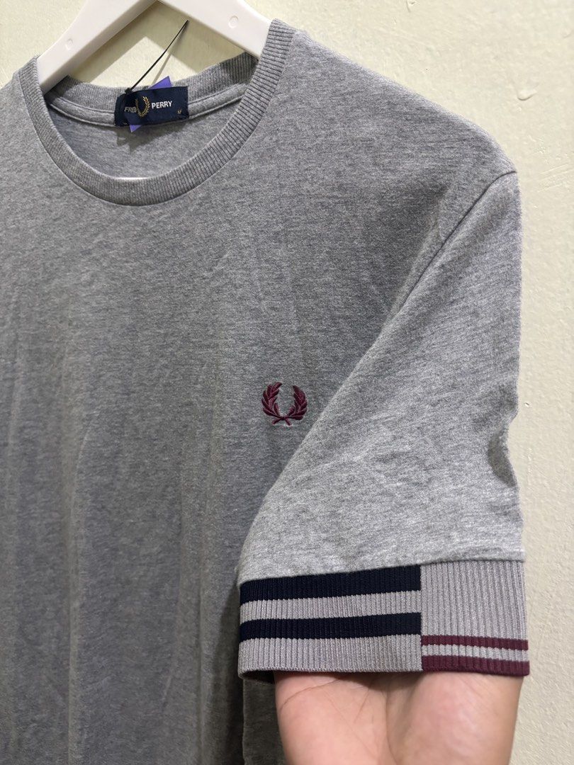 Fred Perry Grey T-Shirt Size M M8529 (Category: Tshirts & Polo Shirts ) located in Daraga. Submitted by hannieldustin (Listing ID 1466063410, Image 2). Description: - Brand: Fred Perry - Style/Model Code: M8529 - Color: Grey - Size: Medium - Condition: Brand new with tags attached - Design Details: Ribbed crew neck, short sleeves with maroon and dark blue striped cuffs, and embroidered laurel wreath logo on the chest - Origin: Made in China - 19.
