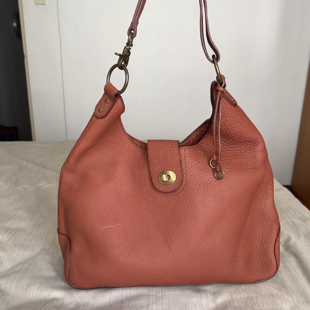 Genuine Leather Hobo Shoulder Bag (Category: Shoulder Bags) located in Pasig City. Submitted by jenscloset86 (Listing ID 1465986611, Image 1). Description: Measurement (in inches): Length: 10.5” Height: 5” Strap: 20” • Brown pebbled genuine leather with brass hardware. • Structured base with a stylish slouchy top • Includes an adjustable strap with ring attachments • Flaw: Minor scuff mark near the bottom front (barely noticeable)..