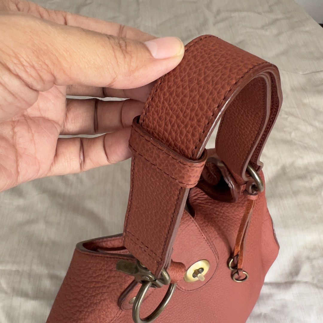 Genuine Leather Hobo Shoulder Bag (Category: Shoulder Bags) located in Pasig City. Submitted by jenscloset86 (Listing ID 1465986611, Image 3). Description: Measurement (in inches): Length: 10.5” Height: 5” Strap: 20” • Brown pebbled genuine leather with brass hardware. • Structured base with a stylish slouchy top • Includes an adjustable strap with ring attachments • Flaw: Minor scuff mark near the bottom front (barely noticeable)..