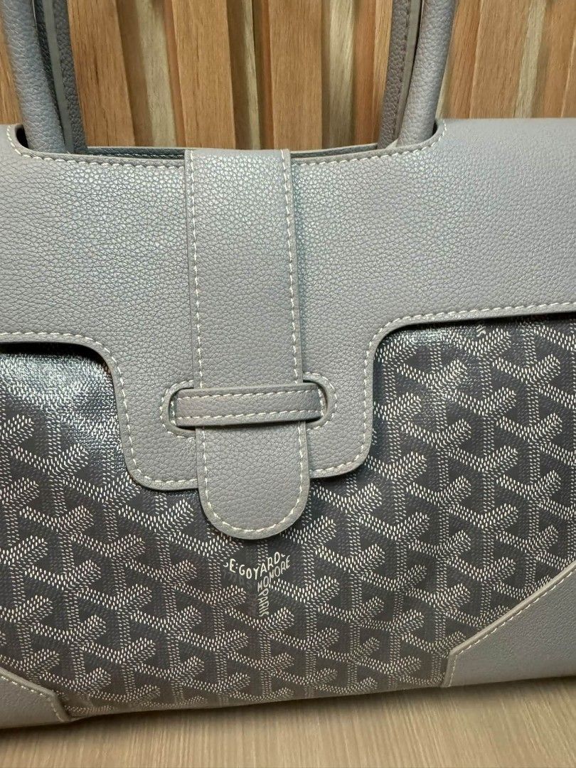 Goyard Saumur Grey Tote Bag (Category: Luxury Bags & Wallets) located in Manila. Submitted by goodbuying_items0211 (Listing ID 1466124255, Image 2). Description: Grey leather tote with Goyard monogram canvas panels. Wooden accent bar across the back. Structured top handle design with a front flap closure and buckle strap. Clean stitching throughout. Sturdy grey handles and reinforced corner patches..