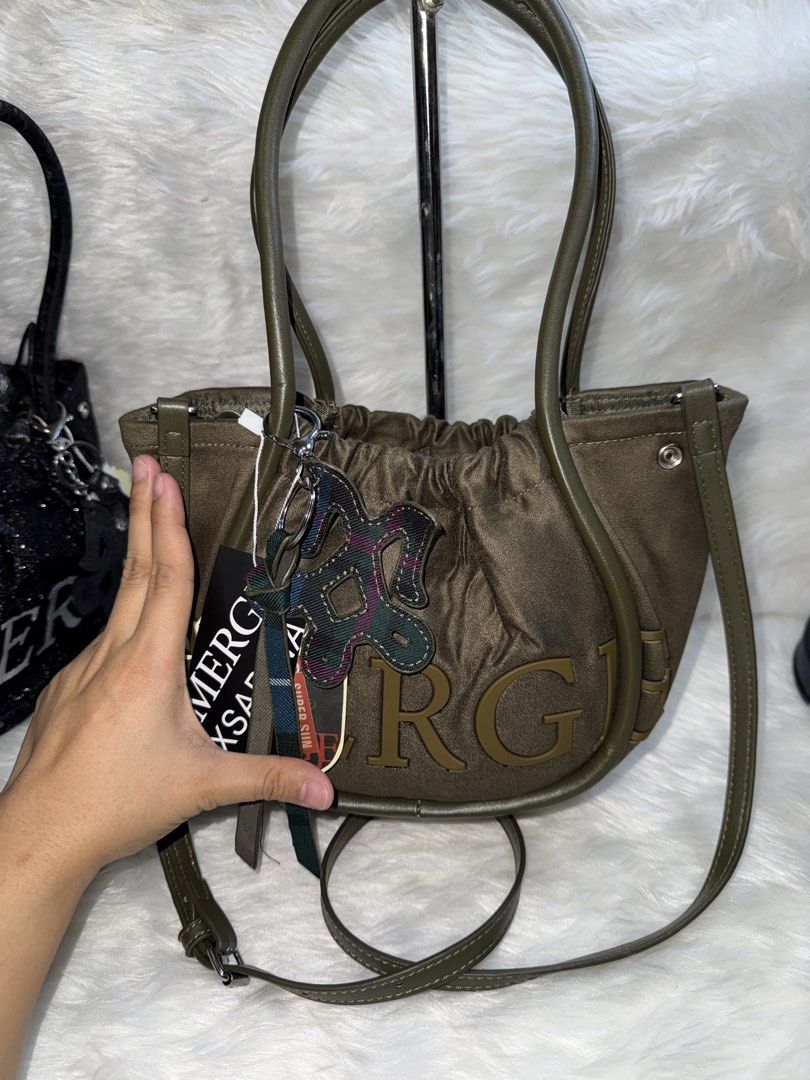 Green MERCH Crossbody Bag with Pouch (Category: Cross-body Bags) located in Taguig. Submitted by roseanneramirez (Listing ID 1466026258, Image 2). Description: - Brand new with tags attached - Trendy olive green design with chunky 'MERCH' lettering - Dual top handles and a detachable, adjustable shoulder strap - Multiple interior compartments for easy organization - Includes a matching plaid drawstring inner pouch - Comes with a stylish patterned