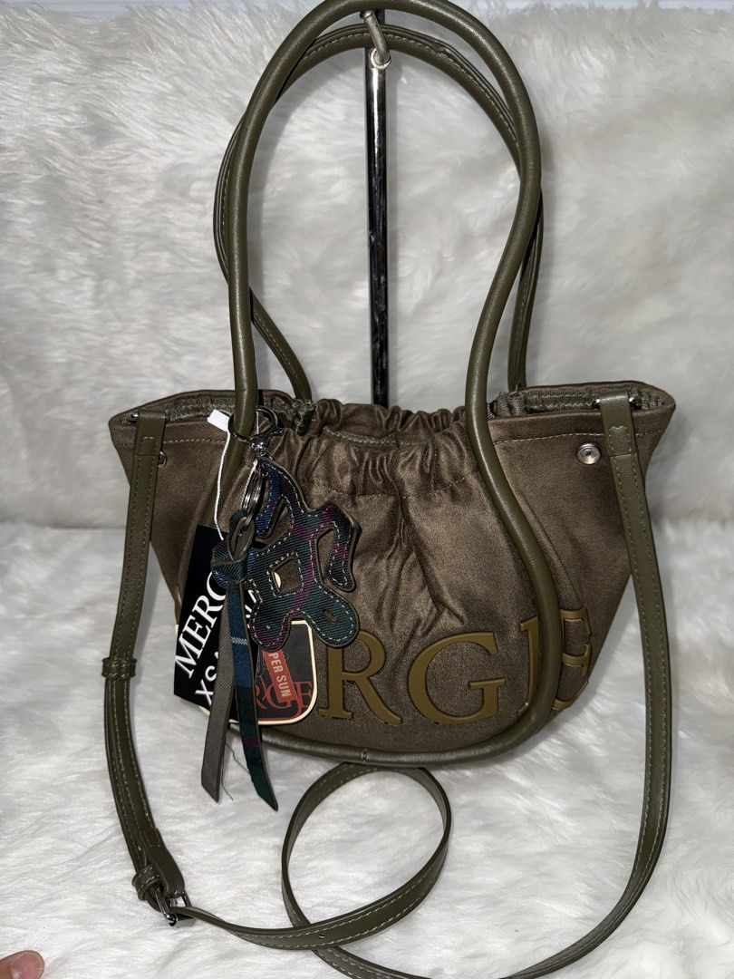 Green MERCH Crossbody Bag with Pouch (Category: Cross-body Bags) located in Taguig. Submitted by roseanneramirez (Listing ID 1466026258, Image 1). Description: - Brand new with tags attached - Trendy olive green design with chunky 'MERCH' lettering - Dual top handles and a detachable, adjustable shoulder strap - Multiple interior compartments for easy organization - Includes a matching plaid drawstring inner pouch - Comes with a stylish patterned