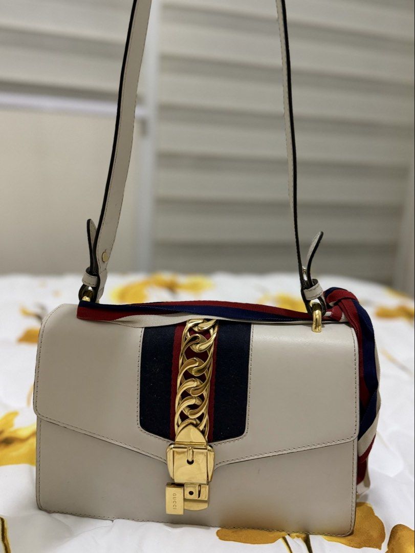 Gucci White Sylvie Small Shoulder Bag (Category: Luxury Bags & Wallets) located in Manila. Submitted by karlainoue (Listing ID 1465462132, Image 2). Description: Authentic Gucci Sylvie shoulder bag in classic white leather Includes an adjustable leather shoulder strap and a detachable ribbon bow Minor surface marks and scuffs on the exterior; visible staining on the interior suede lining Dust bag and card included Bought in Japan.