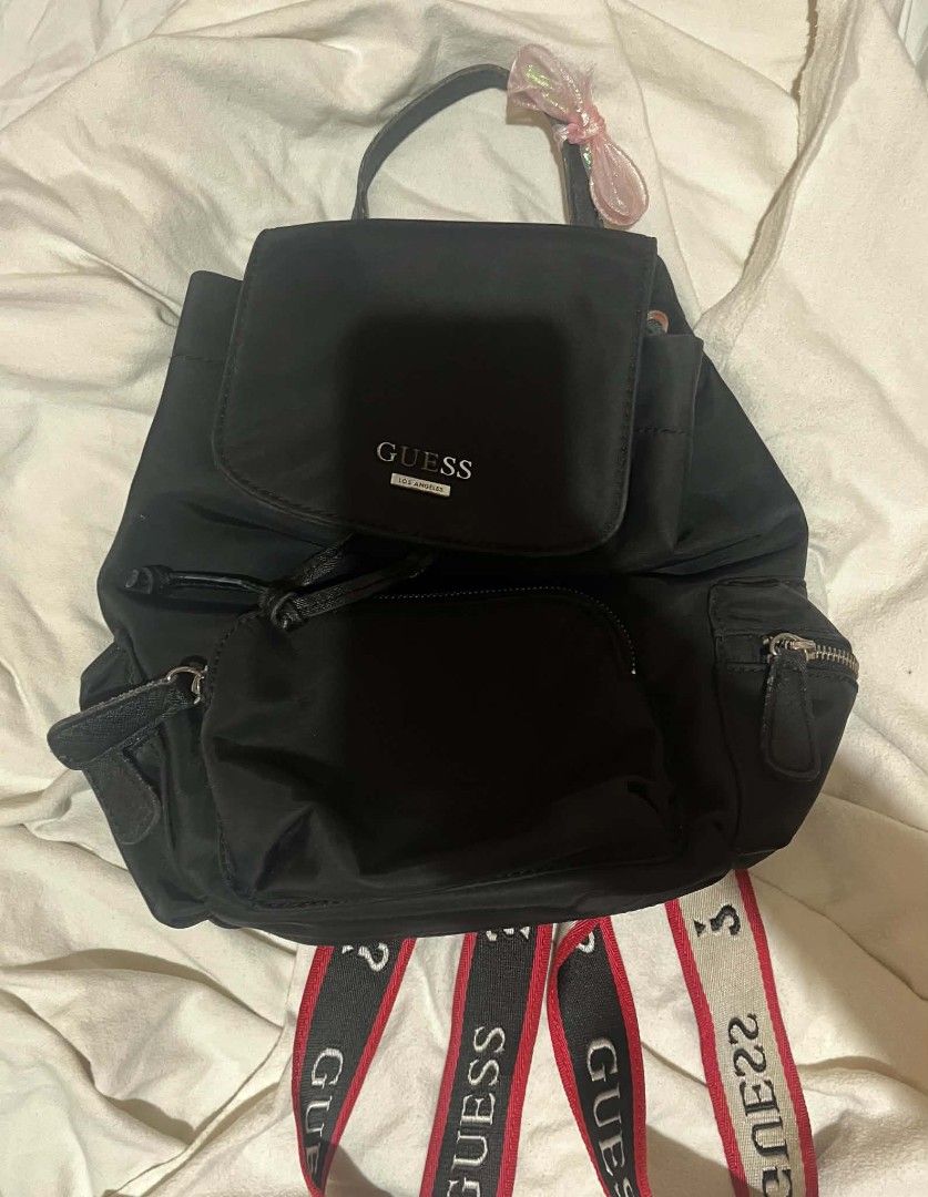 Guess Black Nylon Backpack with Logo Straps (Category: Backpacks) located in Taguig. Submitted by mikacxz (Listing ID 1466059117, Image 1). Description: - Brand: Guess - Material: Durable black nylon - Design: Striking red and white logo straps - Preloved / used but still in good and usable condition. - All compartments and zippers are functional. - Has minor signs of use; please manage expectations and see photos for actual condition. RFS: Declu