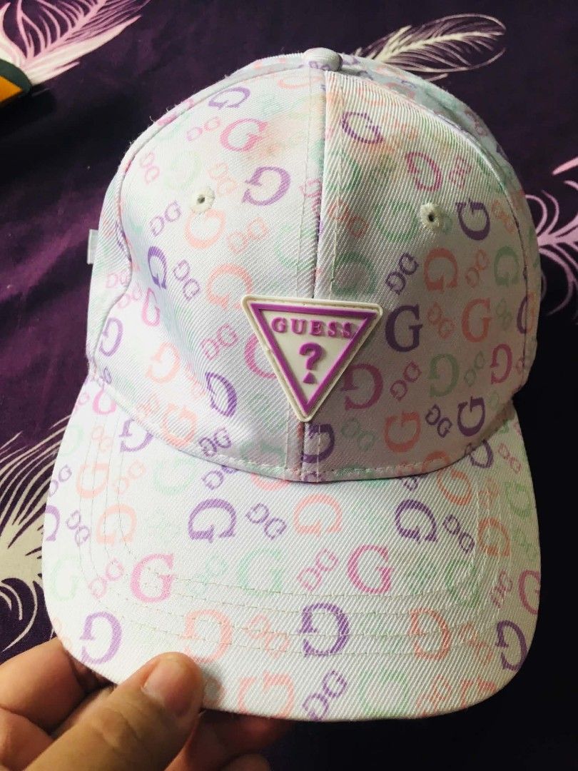 GUESS Monogram Print Baseball Cap (Category: Hats & Beanies) located in Cainta. Submitted by sjprelovedbotique (Listing ID 1466079973, Image 1). Description: - Authentic GUESS baseball cap - Pastel monogram print (pink, purple, green on white) - Raised rubberized GUESS triangle logo patch - Adjustable metal strap for a customized fit - Condition: Shows slight yellowish discoloration along the inner sweatband from previous wear - Perfect for casua