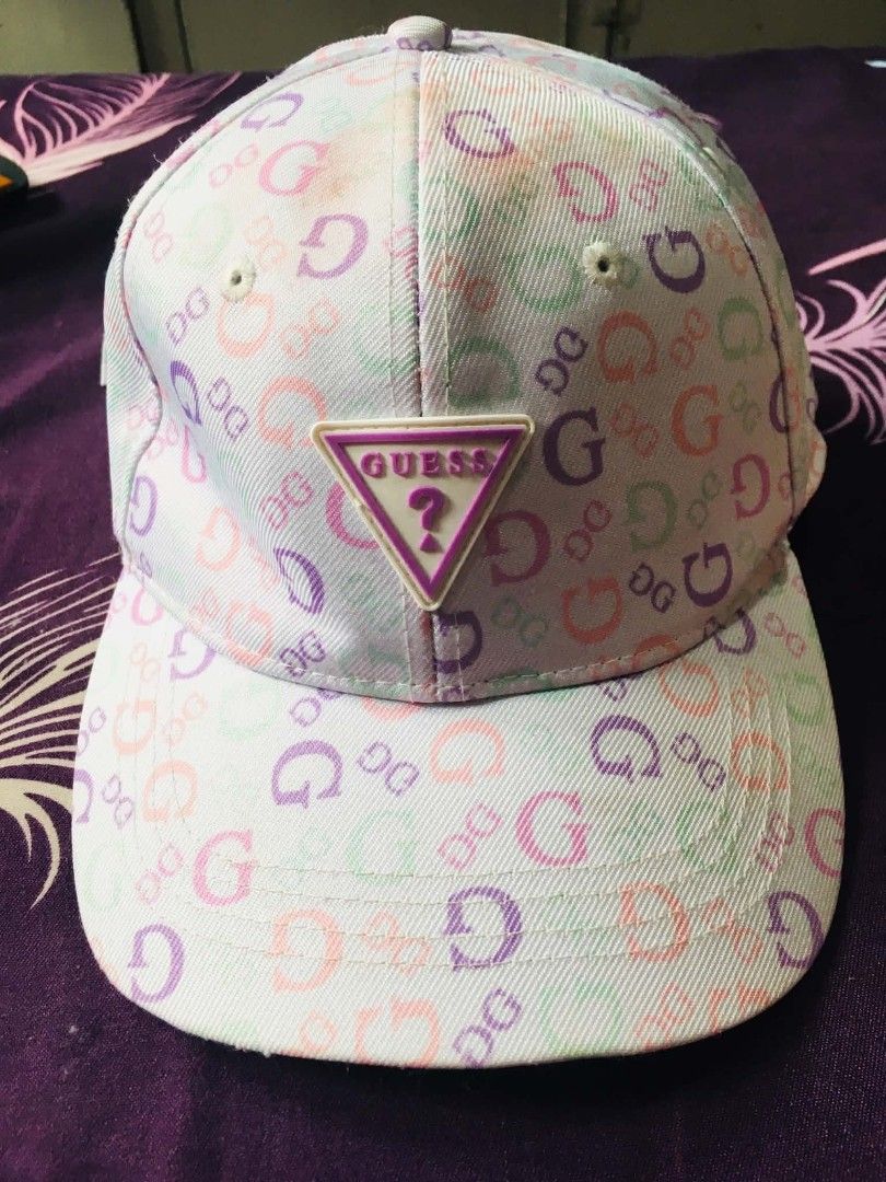 GUESS Monogram Print Baseball Cap (Category: Hats & Beanies) located in Cainta. Submitted by sjprelovedbotique (Listing ID 1466079973, Image 2). Description: - Authentic GUESS baseball cap - Pastel monogram print (pink, purple, green on white) - Raised rubberized GUESS triangle logo patch - Adjustable metal strap for a customized fit - Condition: Shows slight yellowish discoloration along the inner sweatband from previous wear - Perfect for casua