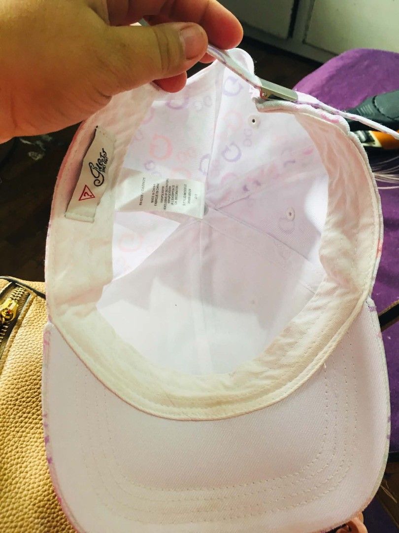 GUESS Monogram Print Baseball Cap (Category: Hats & Beanies) located in Cainta. Submitted by sjprelovedbotique (Listing ID 1466079973, Image 3). Description: - Authentic GUESS baseball cap - Pastel monogram print (pink, purple, green on white) - Raised rubberized GUESS triangle logo patch - Adjustable metal strap for a customized fit - Condition: Shows slight yellowish discoloration along the inner sweatband from previous wear - Perfect for casua