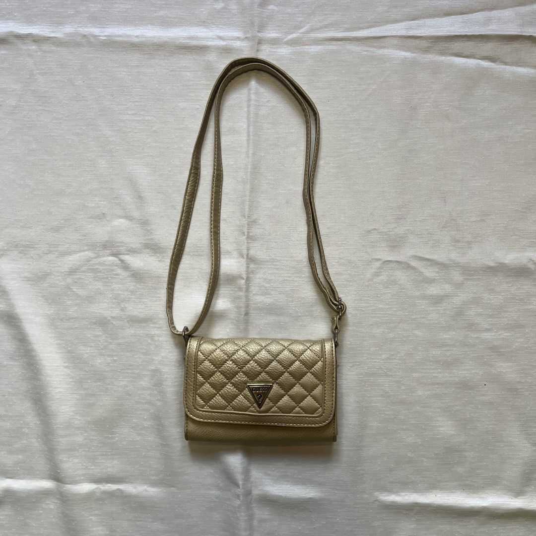 GUESS Quilted Crossbody Bag Gold (Category: Cross-body Bags) located in Dasmarinas. Submitted by minx203 (Listing ID 1466103641, Image 1). Description: - Brand: GUESS crossbody bag - Color: Elegant Gold with quilted leather-look exterior - Details: Iconic triangle metal logo plate on the front flap - Interior: Black fabric lining with built-in card slots for easy organization - Closure: Secure magnetic snap closure - Strap: Long shoulder strap wi