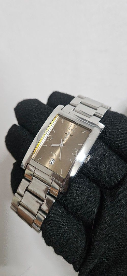 Guess Steel rectangular wristwatch with brown dial (Category: Women's Watches) located in Santa Maria. Submitted by rommelmateo (Listing ID 1466111878, Image 1). Description: - Brand: Guess - Case: Rectangular steel case with side crown - Dial: Brown dial with silver numerals (12, 3, 9) and date window at 4 o'clock - Strap: Silver-tone stainless steel bracelet with deployment clasp stamped Steel - Condition: Normal signs of handling on the metal 