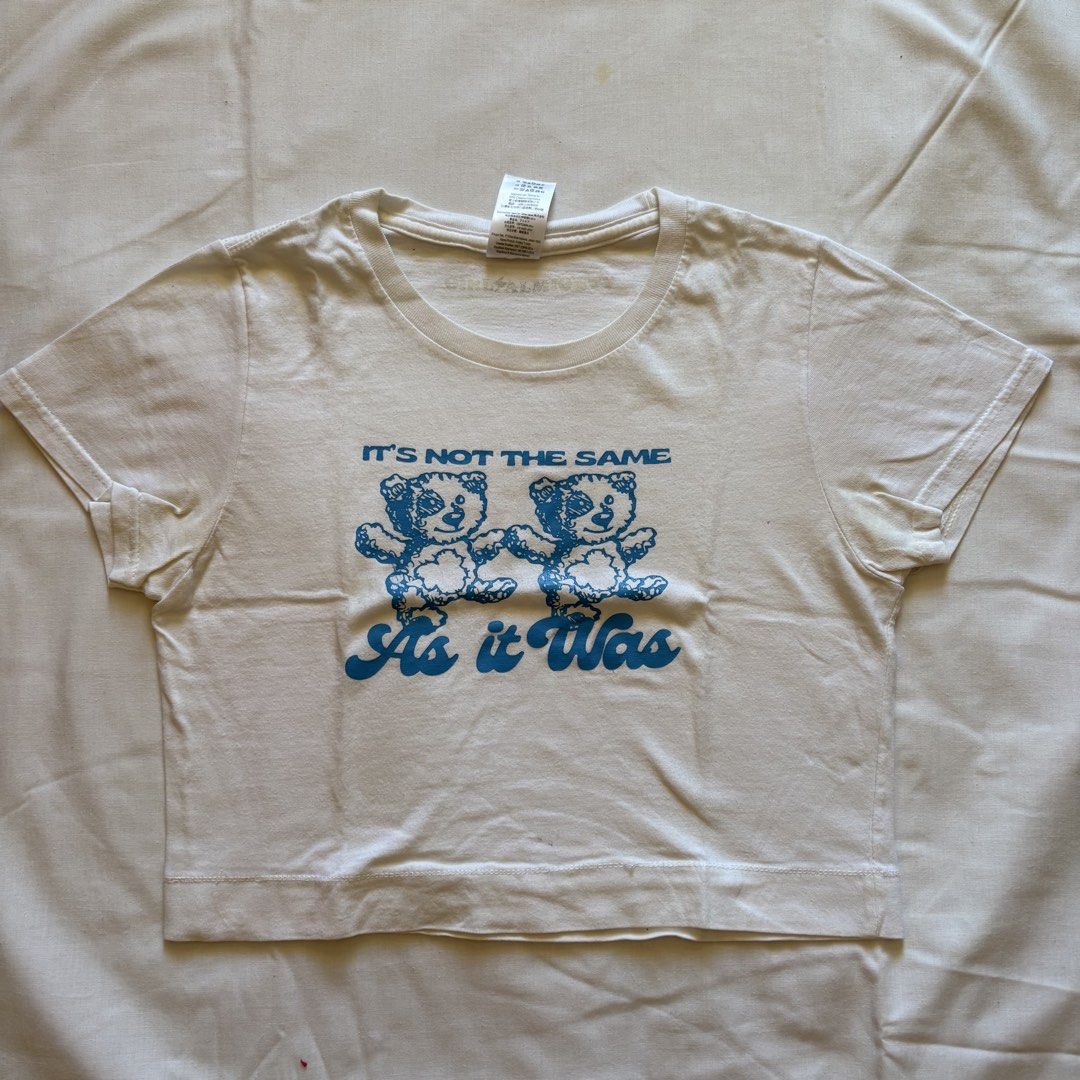 Harry Styles As It Was Bear Crop Top White (Category: Shirts) located in Calabanga. Submitted by vrncashane (Listing ID 1466125948, Image 1). Description: - Color: White - Style: Short-sleeve crop top with rounded neckline and regular fit - Design: Blue teddy bear graphic print with 'IT'S NOT THE SAME As it Was' text - Material: Soft and breathable cotton fabric - Condition: Excellent, clean with no stains or marks (ready to wear).