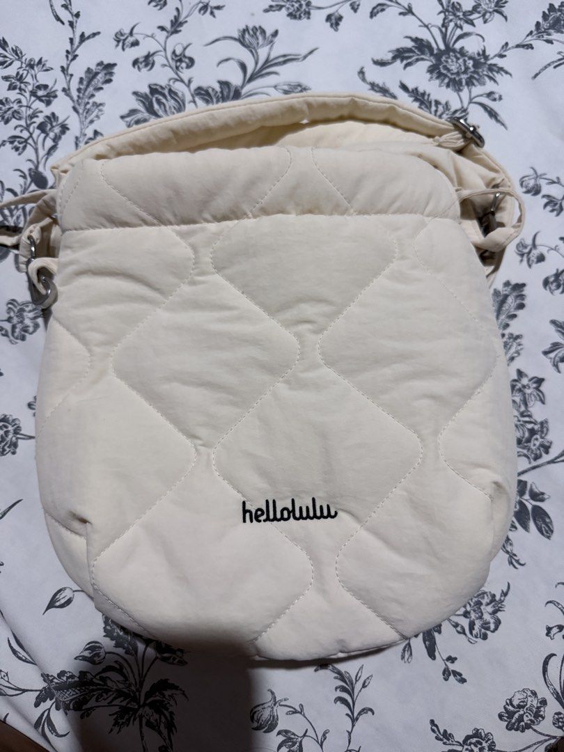 Hellolulu Quilted Crossbody Bag Off White (Category: Cross-body Bags) located in Cebu City. Submitted by adrieyen (Listing ID 1466048214, Image 1). Description: - Brand: Hellolulu - Color: Off-white - Material: Soft puffy fabric with diamond quilting - Closure: Top drawstring - Interior: Lined with light fabric and a built-in zip pocket - Strap: Removable and adjustable with metal clips - Flaws: Minor smudge marks on the exterior near the side st