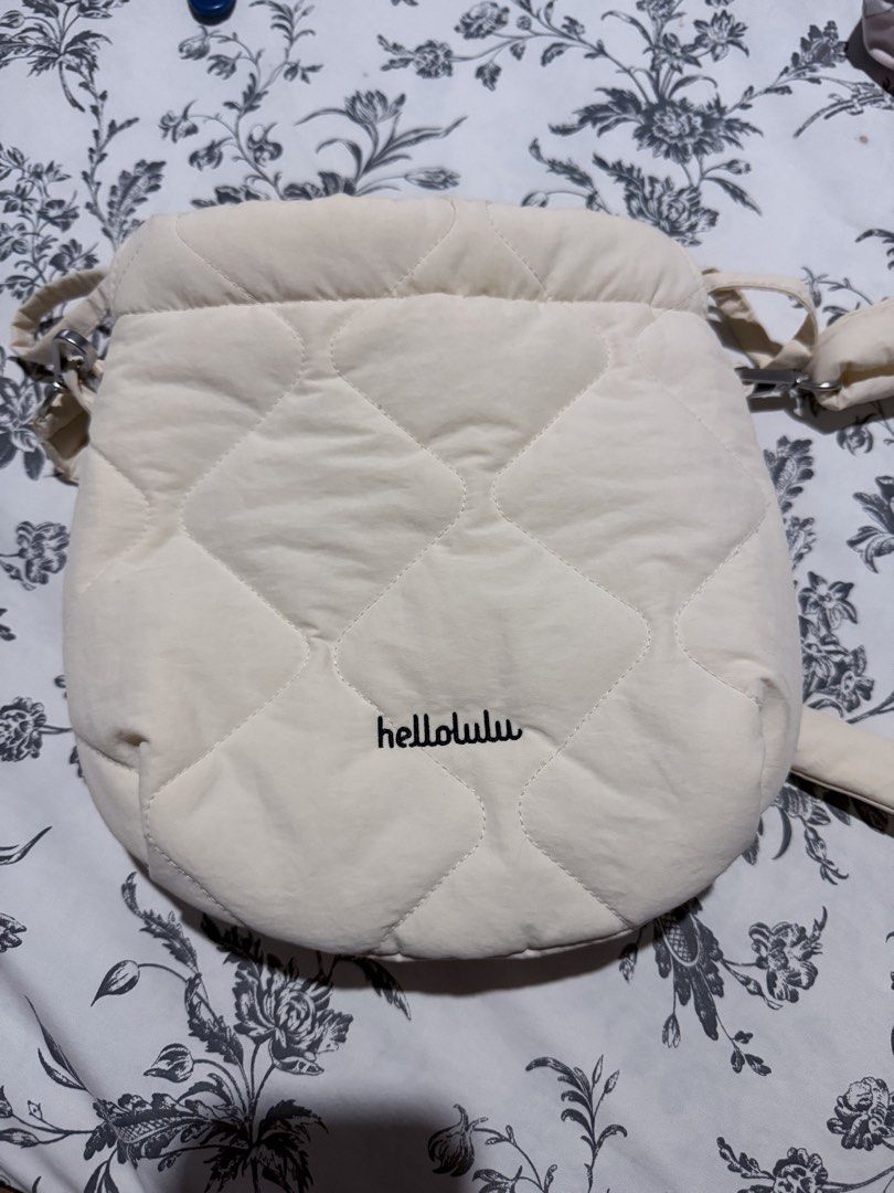 Hellolulu Quilted Crossbody Bag Off White (Category: Cross-body Bags) located in Cebu City. Submitted by adrieyen (Listing ID 1466048214, Image 2). Description: - Brand: Hellolulu - Color: Off-white - Material: Soft puffy fabric with diamond quilting - Closure: Top drawstring - Interior: Lined with light fabric and a built-in zip pocket - Strap: Removable and adjustable with metal clips - Flaws: Minor smudge marks on the exterior near the side st