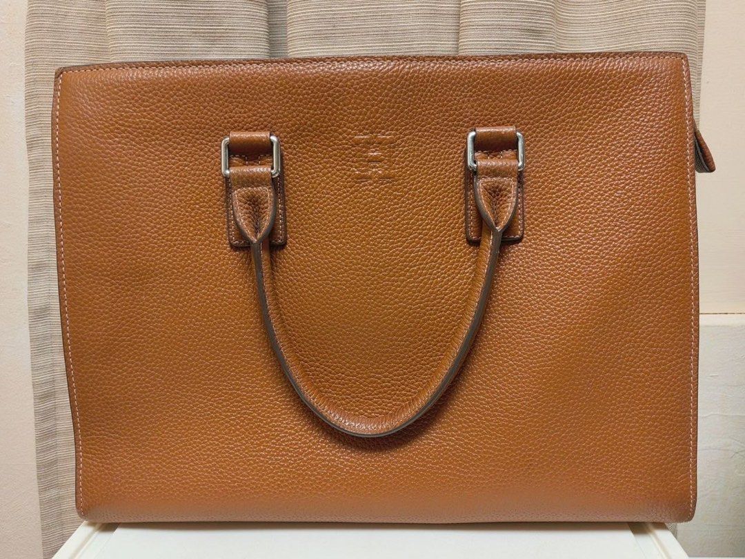 Hermes Leather Briefcase Bag (Category: Briefcases) located in Manila. Submitted by junejanuary (Listing ID 1466145236, Image 1). Description: - Color & Material: Tan textured leather - Design: Structured rectangular shape with clean stitching and debossed geometric logo on the front - Hardware: Silver-toned hardware loops with dual top handles - Capacity: Spacious enough to easily fit a laptop and documents - Condition: Brand new/Mint (ready for
