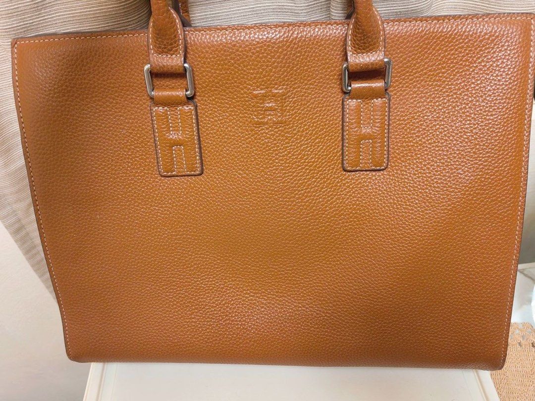 Hermes Leather Briefcase Bag (Category: Briefcases) located in Manila. Submitted by junejanuary (Listing ID 1466145236, Image 2). Description: - Color & Material: Tan textured leather - Design: Structured rectangular shape with clean stitching and debossed geometric logo on the front - Hardware: Silver-toned hardware loops with dual top handles - Capacity: Spacious enough to easily fit a laptop and documents - Condition: Brand new/Mint (ready for