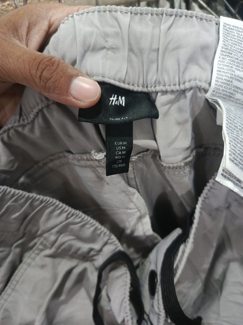 H&M Slim Fit Grey Cargo Pants Size M (Category: Trousers) located in City of Isabela. Submitted by warmbird.d06e6f (Listing ID 1466095315, Image 2). Description: - Brand/Model: H&M Cargo Pants - Fit: Slim fit - Size: Medium (EUR M) - Waistband: Elastic with black adjustable drawstring - Pockets: Secure side zippered pockets - Details: Trendy coordinate text print near the lower leg hem - Condition: Excellent.