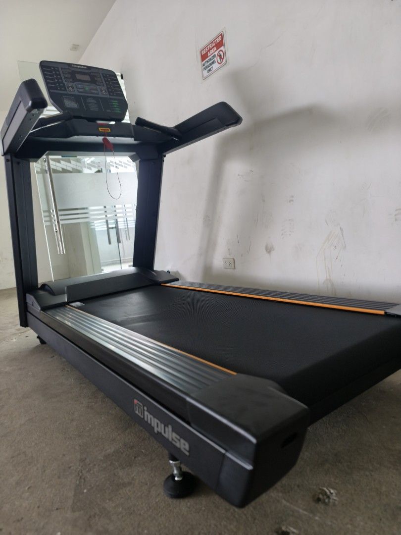 Impulse AC2990 COMMERCIAL TREADMILL (Category: Cardio & Fitness Machines) located in Caloocan City. Submitted by fitness.source.ph (Listing ID 1465995214, Image 3). Description: - Heavy-duty Impulse commercial treadmill in sleek matte black with striking orange accents - Large digital console display with multiple tracking buttons, cup holders, and red safety key tether - Solid construction featuring sturdy handrails and adjustable leveling feet 