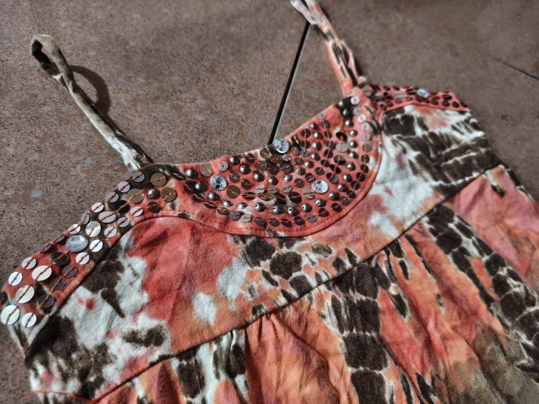 Justice Tie-Dye Sequin Camisole Tank Top (Category: Sleeveless) located in Manila. Submitted by sunnysideup.tree (Listing ID 1466028511, Image 2). Description: Justice camisole top in vibrant tie-dye print. Orange, brown, and pink colorway with white contrast patches. Scoop neckline decorated with metallic sequins and beads. Spaghetti straps. Flowy, relaxed fit through the body. Tag size 10 inside the collar. Soft cotton blend material, breathabl