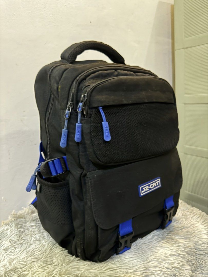 JZ-CAT Black and Blue Backpack (Category: Backpacks) located in Urdaneta. Submitted by kathleenja24136 (Listing ID 1465958334, Image 3). Description: - Color: Sleek black with eye-catching blue straps and zipper pulls - Storage: Main compartment, front pocket with mesh detail and buckle flap, and side mesh pockets for water bottles - Comfort: Padded shoulder straps and breathable mesh back panel - Portability: Sturdy top handle for easy grabbing 