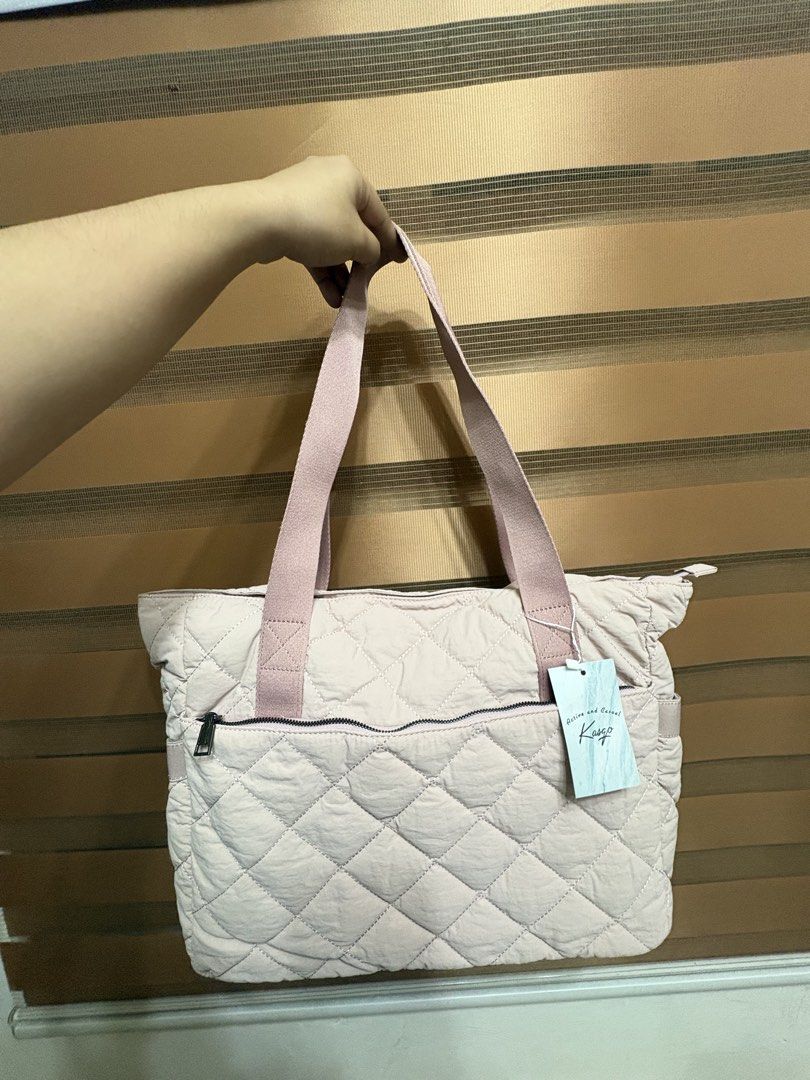 Kasgo Quilted Tote Bag Pink (Category: Tote Bags) located in Manila. Submitted by maemey_botique23 (Listing ID 1466081569, Image 2). Description: Kasgo quilted tote bag in light pink. Quilted nylon material with sturdy pink shoulder straps. Exterior zippered pocket on the front. Fully lined interior with multiple compartments, padded laptop sleeve, and a matching small quilted pouch included. Zipper closure on top. Brand new in original plastic p