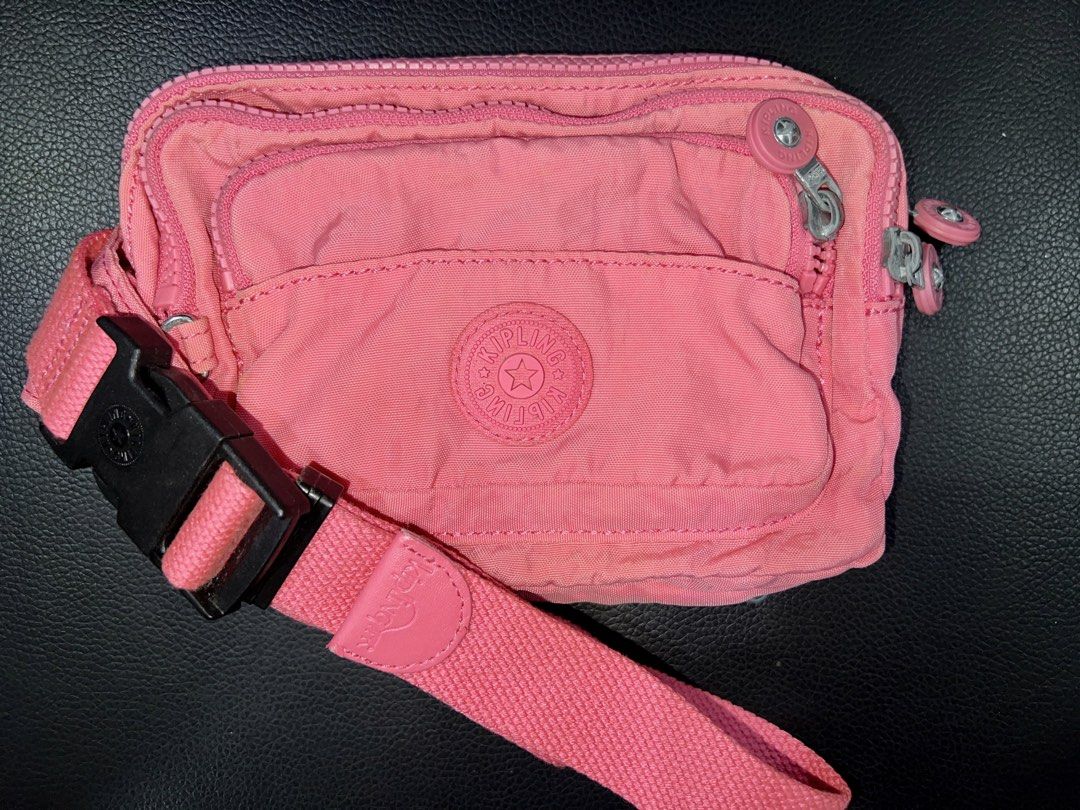 Kipling Pink Fanny Pack Crossbody Bag (Category: Cross-body Bags) located in Baguio. Submitted by destashglam (Listing ID 1466062633, Image 1). Description: - Authentic Kipling fanny pack in a vibrant bright pink shade - Multiple zipped compartments for easy organization - Secure adjustable strap with a durable black plastic buckle - Silver-tone hardware and signature round logo patch - Interior features light lining and an extra zip pocket - Per