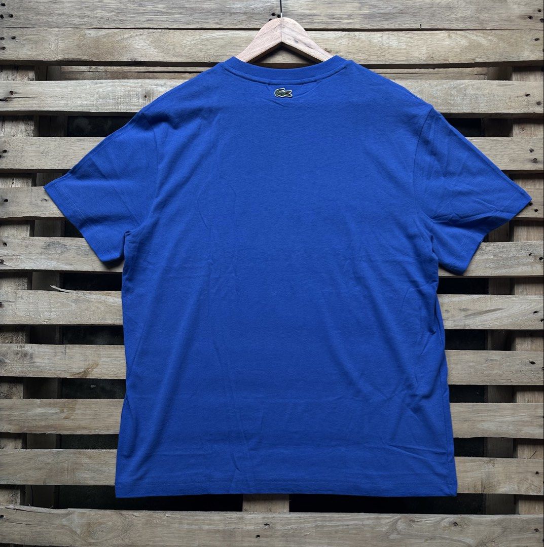 Lacoste Oval Logo Regular Fit T-Shirt Blue (Category: Tshirts & Polo Shirts ) located in Manila. Submitted by dough_lux (Listing ID 1466070138, Image 2). Description: - Brand: Lacoste - Style: Regular fit crew neck short sleeve t-shirt - Size: US XL / FR 6 - Color: Blue with a large white oval front graphic and branding - Details: Small green contrast trim inside collar and tiny embroidered crocodile logo near the back neckline - Condition: Excel