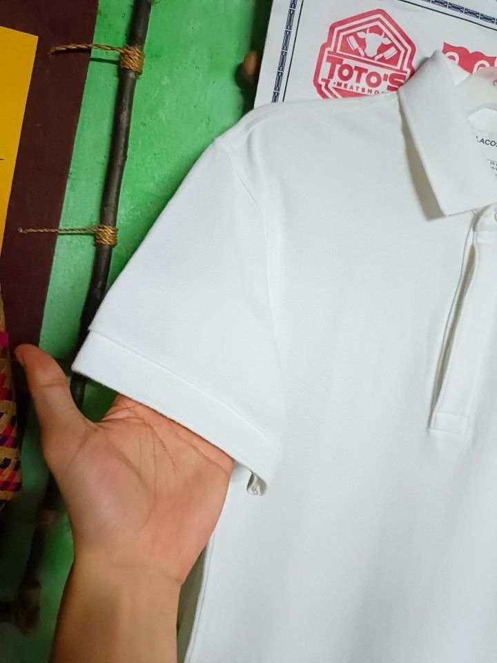 Lacoste White Monogram Polo Shirt Size S (Category: Tshirts & Polo Shirts ) located in Makati City. Submitted by elgamapenumbra (Listing ID 1466078288, Image 3). Description: - Brand: Lacoste - Color: Classic White - Size: FR 3 / US Small - Color rate: 9.5/10 - Material: Soft cotton pique fabric - Fit: Classic fit with short sleeves and ribbed collar - Details: Single button placket with embroidered green crocodile logo on chest - Condition: Exce