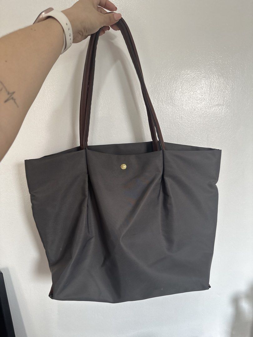 Legato Largo Nylon Tote Bag Grey, Medium (Category: Tote Bags) located in Cainta. Submitted by xyzasisa (Listing ID 1465995649, Image 1). Description: - Brand: Legato Largo - Color: Dark grey nylon with brown leather-look straps - Hardware: Elegant gold details - Pockets: Front pocket with snap button closure and a secure zippered middle compartment inside - Capacity: Roomy interior, easily fits daily essentials - Condition: Clean inside and out,