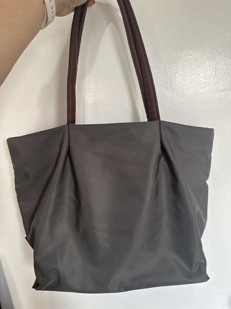 Legato Largo Nylon Tote Bag Grey, Medium (Category: Tote Bags) located in Cainta. Submitted by xyzasisa (Listing ID 1465995649, Image 3). Description: - Brand: Legato Largo - Color: Dark grey nylon with brown leather-look straps - Hardware: Elegant gold details - Pockets: Front pocket with snap button closure and a secure zippered middle compartment inside - Capacity: Roomy interior, easily fits daily essentials - Condition: Clean inside and out,