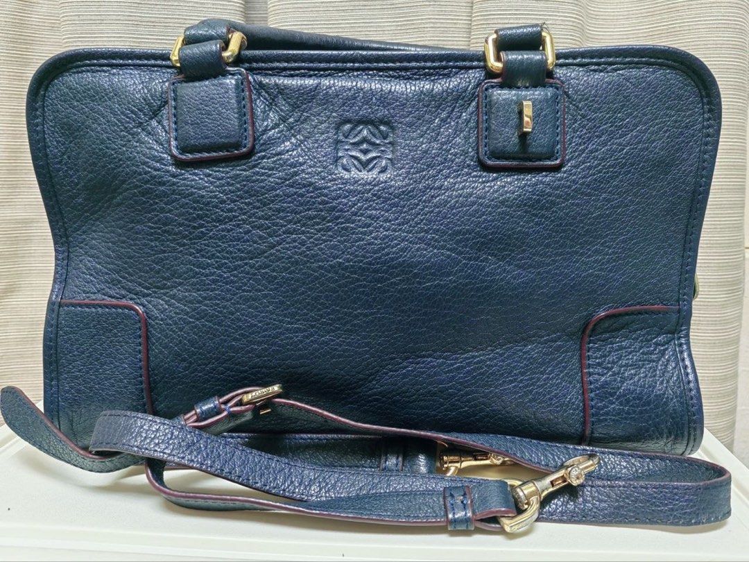 Loewe Blue Leather Amazona bag (Category: Luxury Bags & Wallets) located in Manila. Submitted by junejanuary (Listing ID 1466145374, Image 1). Description: - Loewe blue leather handbag - Striking embossed logo in the center - Elegant gold hardware on handles and strap attachments - Structured shape with chic dark red edge glazing - Double top handles with rectangular loops - Includes matching adjustable leather strap with buckles and clips - Cond