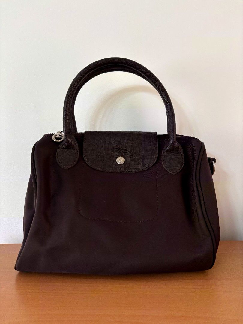 Longchamp Le Pliage Cuir Top Handle Bag Brown (Category: Luxury Bags & Wallets) located in Solano. Submitted by annbusinessell (Listing ID 1466120351, Image 3). Description: - Brand: Longchamp - Color: Dark Brown - Material: Durable nylon and leather trim with silver hardware - Closure: Top zip with signature leather snap flap - Straps: Dual top handles and adjustable fabric shoulder strap - Interior: Clean lining with convenient open pockets - C