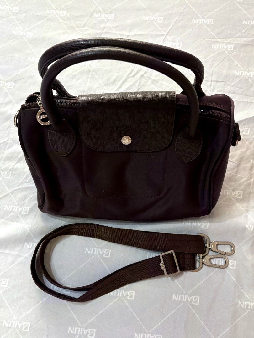 Longchamp Le Pliage Cuir Top Handle Bag Brown (Category: Luxury Bags & Wallets) located in Solano. Submitted by annbusinessell (Listing ID 1466120351, Image 1). Description: - Brand: Longchamp - Color: Dark Brown - Material: Durable nylon and leather trim with silver hardware - Closure: Top zip with signature leather snap flap - Straps: Dual top handles and adjustable fabric shoulder strap - Interior: Clean lining with convenient open pockets - C