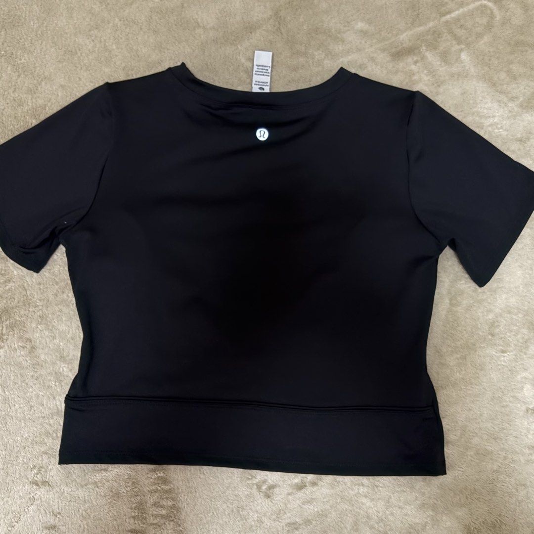 Lululemon Black Short Sleeve Crop Top (Category: Shirts) located in Quezon City. Submitted by annecsj (Listing ID 1466001505, Image 2). Description: - Brand: Lululemon - Color: Classic Black - Style: Short sleeve crop top with a flattering rounded neckline - Material: Ultra-soft, breathable athletic fabric - Details: Signature reflective Lululemon logo on the upper back - Versatility: Pairs effortlessly with high-waisted leggings or shorts for gy