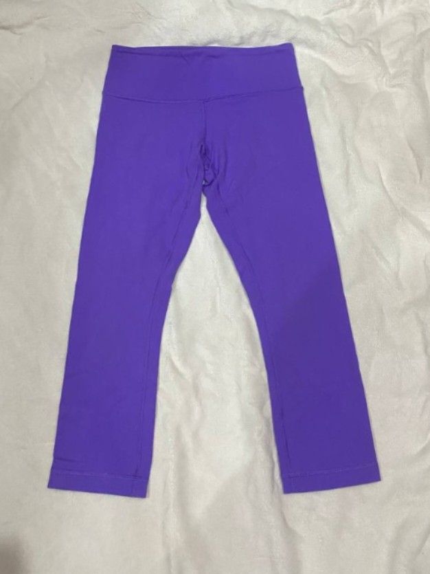 Lululemon Purple Athletic Crop Leggings (Category: Activewear) located in Manila. Submitted by lovelypreloved1497 (Listing ID 1466107640, Image 1). Description: - Brand: Lululemon - Color: Bright purple - Style: Cropped athletic leggings with high-rise waistband - Details: Iconic silver omega logo on back hip - Fit & Fabric: Super stretchy, comfortable fit with strong seams - Condition: Clean, minimal wear on the print - Ideal for: Workouts, yoga