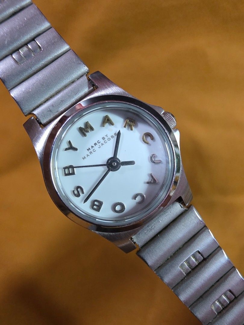 Marc By Marc Jacobs MBM1234 Silver Watch (Category: Women's Watches) located in Rosales. Submitted by akumie30 (Listing ID 1466140045, Image 1). Description: Marc By Marc Jacobs silver tone watch. Model number MBM1234. White dial featuring bold 'MARC BY MARC' letter indexes instead of standard numbers. Stainless steel stretch expansion bracelet. Quartz movement with three-hand analog display. Water resistant to 5 ATM. Case back shows minor surfac