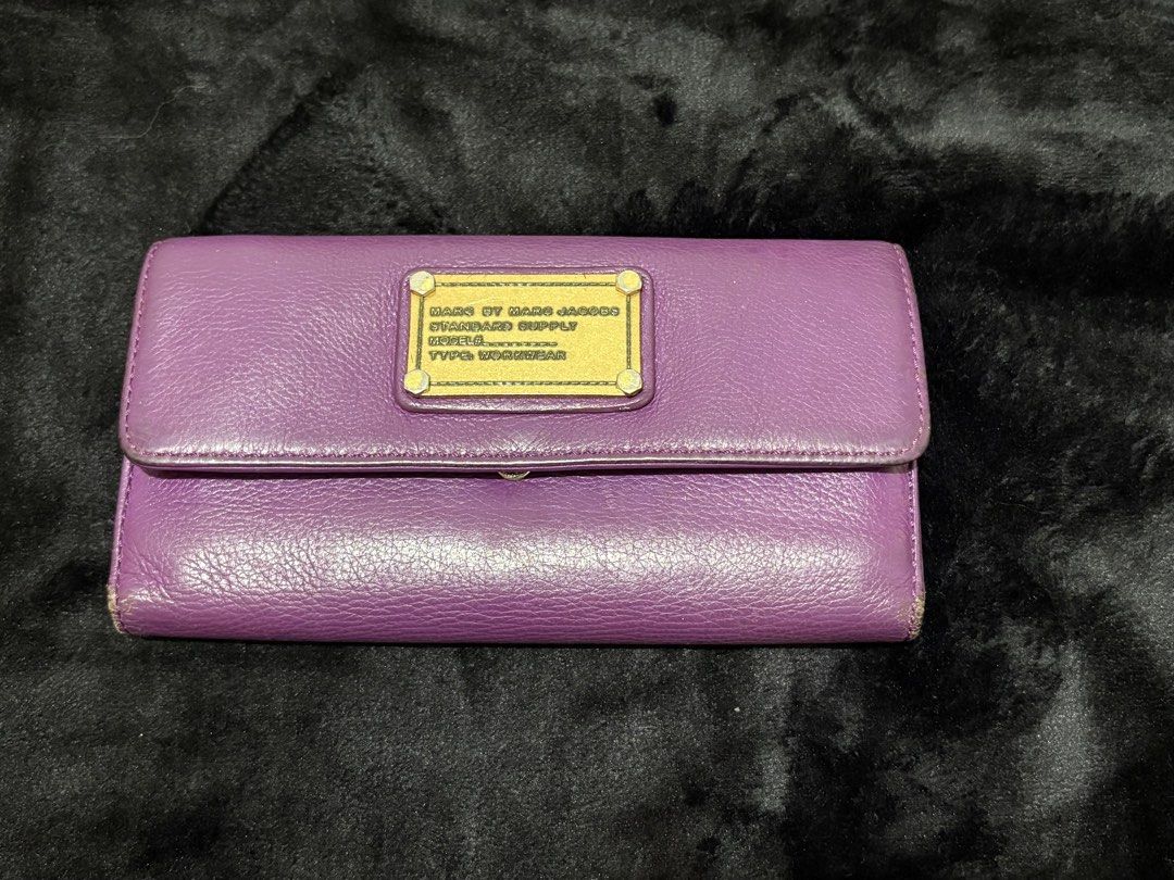 Marc by Marc Jacobs Purple Leather Wallet (Category: Wallets & Card holders) located in Manila. Submitted by nykji96 (Listing ID 1465963803, Image 1). Description: - Brand: Marc by Marc Jacobs - Material: 100% Genuine Purple Leather - Hardware: Gold-tone standard supply plaque - Closure: Secure snap button closure - Interior Features: Multiple card slots, clear ID window, and zippered coin pocket - Lining: Signature black and white logo fabric - 