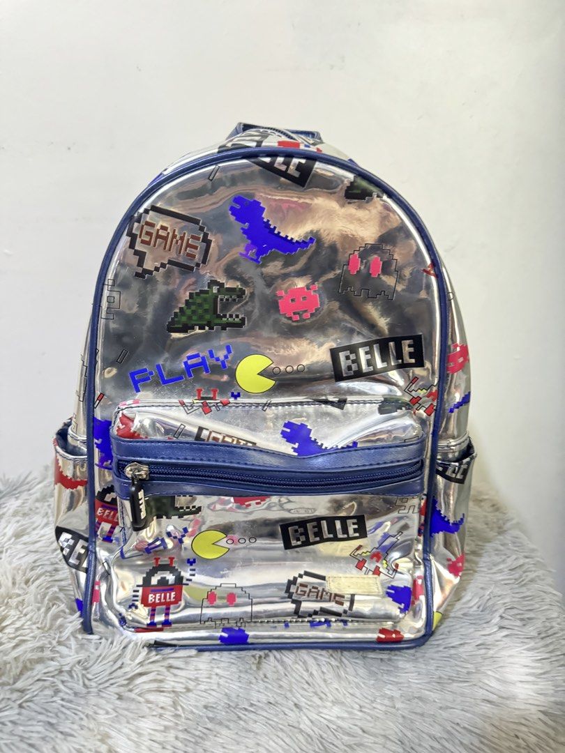 Metallic silver pixel retro arcade video game backpack (Category: Backpacks) located in Urdaneta. Submitted by kathleenja24136 (Listing ID 1465958921, Image 1). Description: - Metallic silver backpack with colorful retro arcade and pixel game graphics - Features Pac-Man ghosts, pixel dinosaurs, spaceships, and dark blue trim - Main compartment with double zippers and a front zipped pocket - Comfortable with adjustable shoulder straps and a top gr