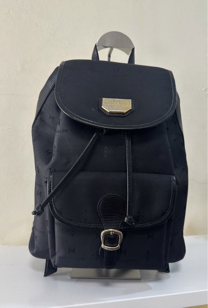 Metrocity Black Monogram Nylon Backpack (Category: Backpacks) located in Cauayan City . Submitted by seraphinecyn (Listing ID 1466124677, Image 1). Description: - Brand: Metrocity - Material: Durable black nylon with all-over monogram pattern - Hardware: Elegant gold-toned logo plaque - Closure: Secure drawstring main closure - Pockets: Convenient front pocket with buckled strap detail - Interior: Spacious main compartment with a structured shape