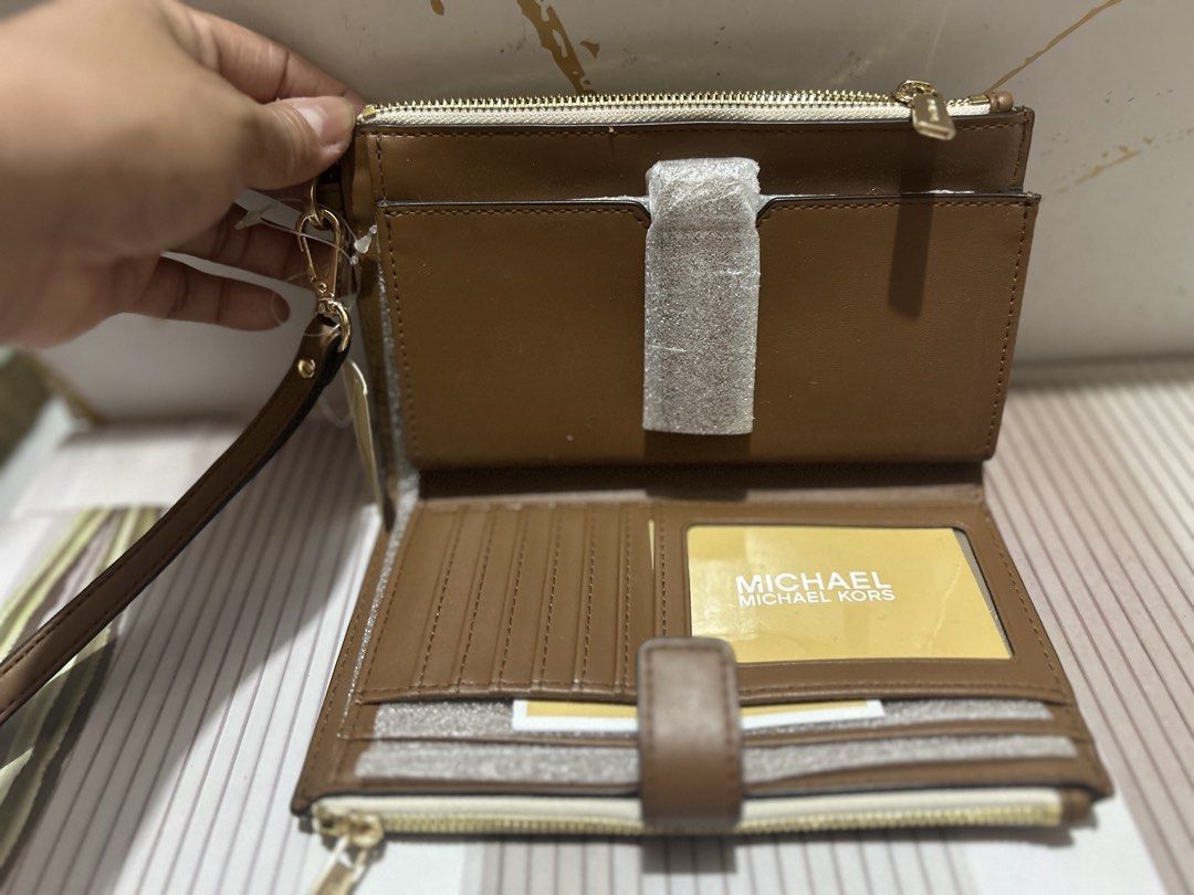 Michael Kors Double Zip Wristlet Wallet Vanilla Brown (Category: Wallets & Card holders) located in Manila. Submitted by trendsby_t (Listing ID 1466144894, Image 3). Description: - Brand: Michael Kors - Color: Vanilla signature logo print with brown leather trim - Hardware: Gold-tone - Compartments: Double zip closure with multiple card slots, clear ID window, and slip pockets - Strap: Detachable wrist strap - Condition: Brand new with protective