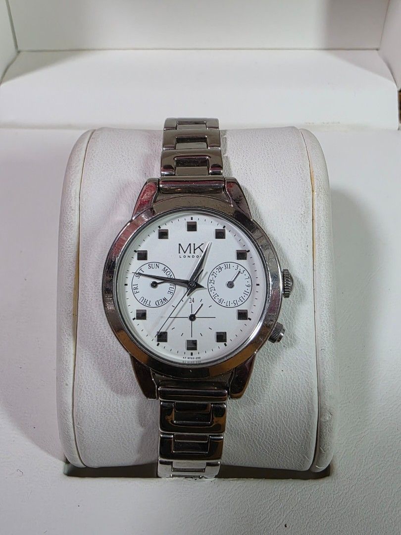 Michiko London Silver Watch with White Dial (Category: Women's Watches) located in Rosales. Submitted by akumie30 (Listing ID 1466134590, Image 1). Description: - Brand: MK London - Color: Silver-tone with clean white dial - Features: Day and date subdials, silver hour markers and hands, side push buttons - Strap: Link bracelet strap with standard clasp closure - Style: Classic everyday timepiece, perfect for casual or formal outfits Original Wat