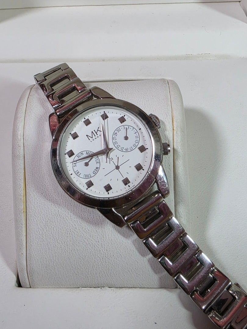 Michiko London Silver Watch with White Dial (Category: Women's Watches) located in Rosales. Submitted by akumie30 (Listing ID 1466134590, Image 2). Description: - Brand: MK London - Color: Silver-tone with clean white dial - Features: Day and date subdials, silver hour markers and hands, side push buttons - Strap: Link bracelet strap with standard clasp closure - Style: Classic everyday timepiece, perfect for casual or formal outfits Original Wat