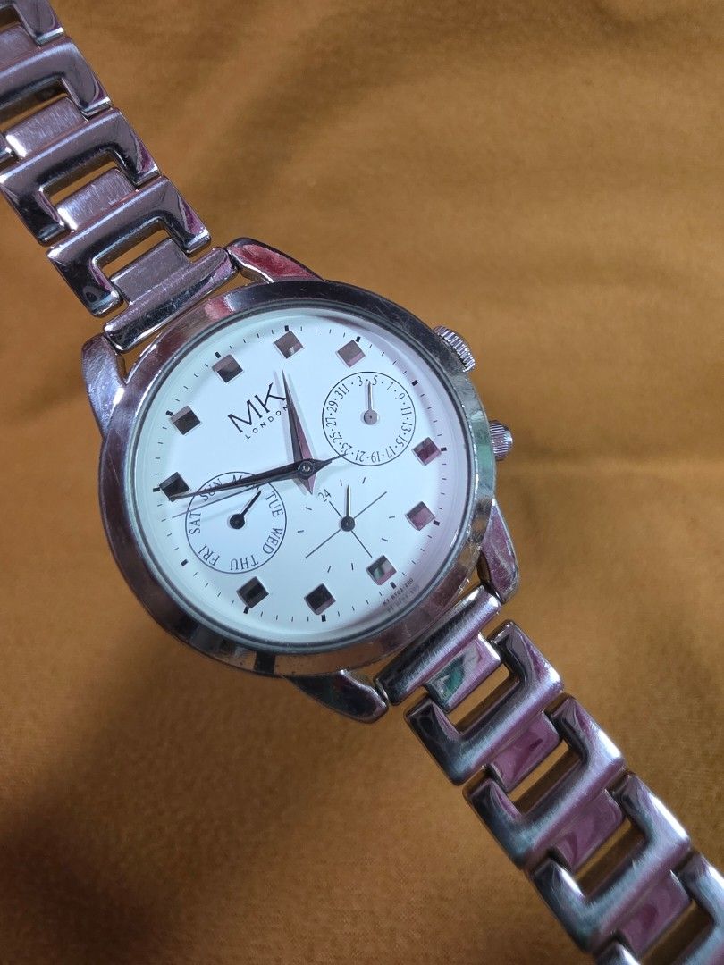 Michiko London Silver Watch with White Dial (Category: Women's Watches) located in Rosales. Submitted by akumie30 (Listing ID 1466134590, Image 3). Description: - Brand: MK London - Color: Silver-tone with clean white dial - Features: Day and date subdials, silver hour markers and hands, side push buttons - Strap: Link bracelet strap with standard clasp closure - Style: Classic everyday timepiece, perfect for casual or formal outfits Original Wat