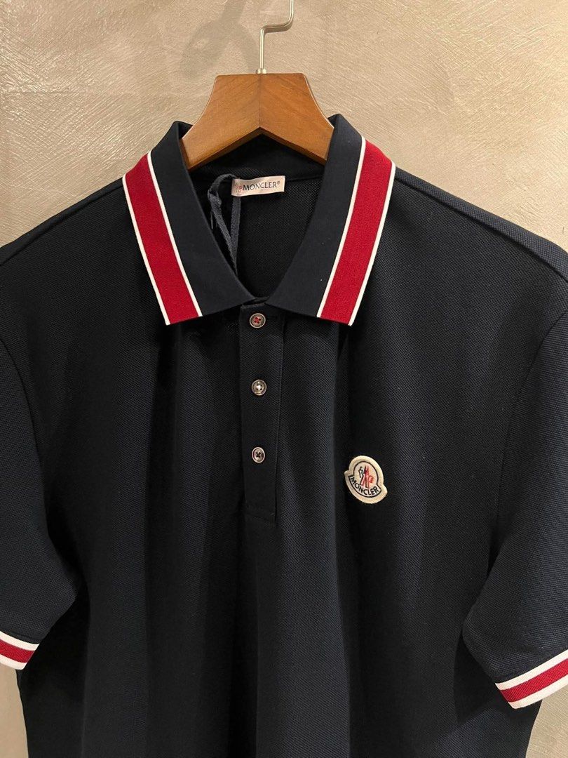Moncler Pique Polo Shirt (Category: Tshirts & Polo Shirts ) located in Imus. Submitted by vdc.apparel (Listing ID 1465955880, Image 2). Description: Moncler Navy blue cotton piqué polo shirt tricolor red and white tipping accents on the collar and cuffs, along with the brand’s signature felt logo patch on the chest..