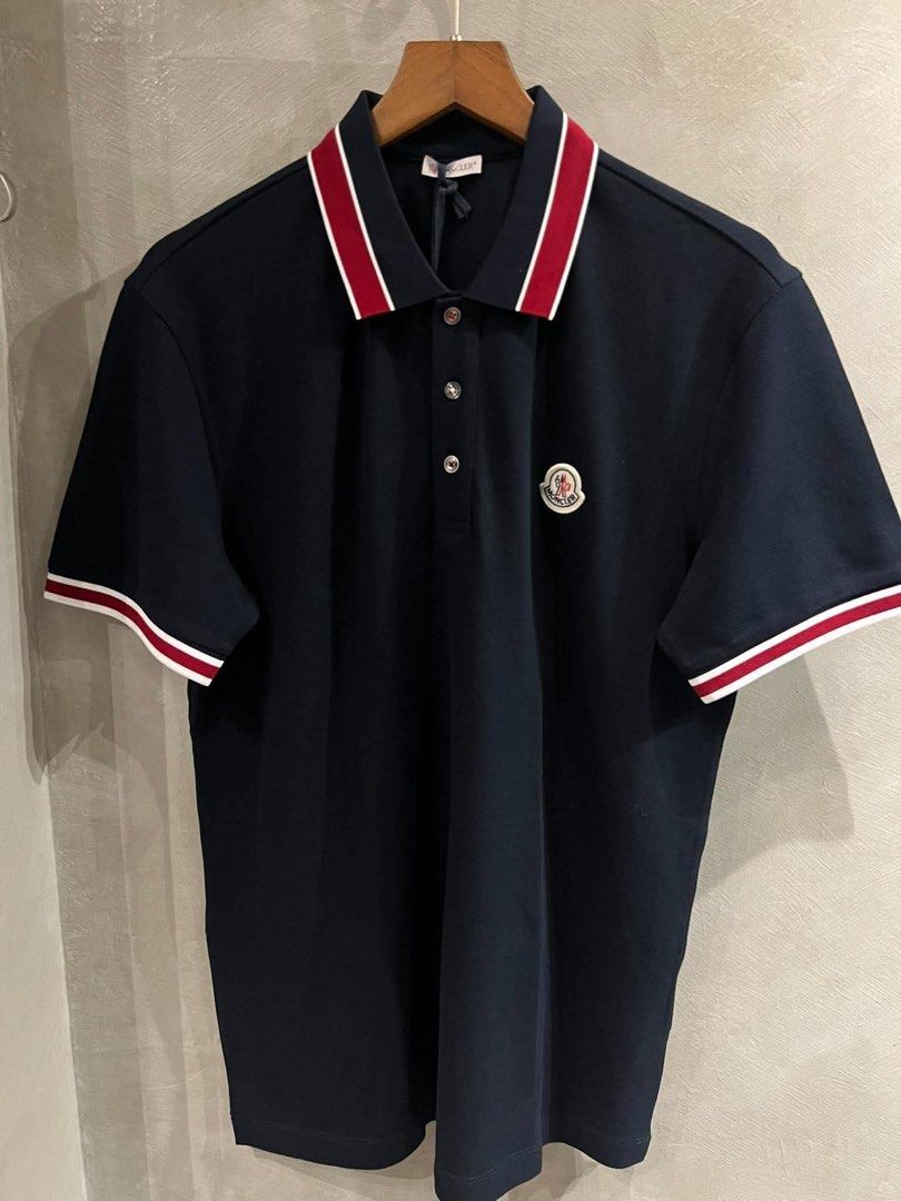 Moncler Pique Polo Shirt (Category: Tshirts & Polo Shirts ) located in Imus. Submitted by vdc.apparel (Listing ID 1465955880, Image 1). Description: Moncler Navy blue cotton piqué polo shirt tricolor red and white tipping accents on the collar and cuffs, along with the brand’s signature felt logo patch on the chest..