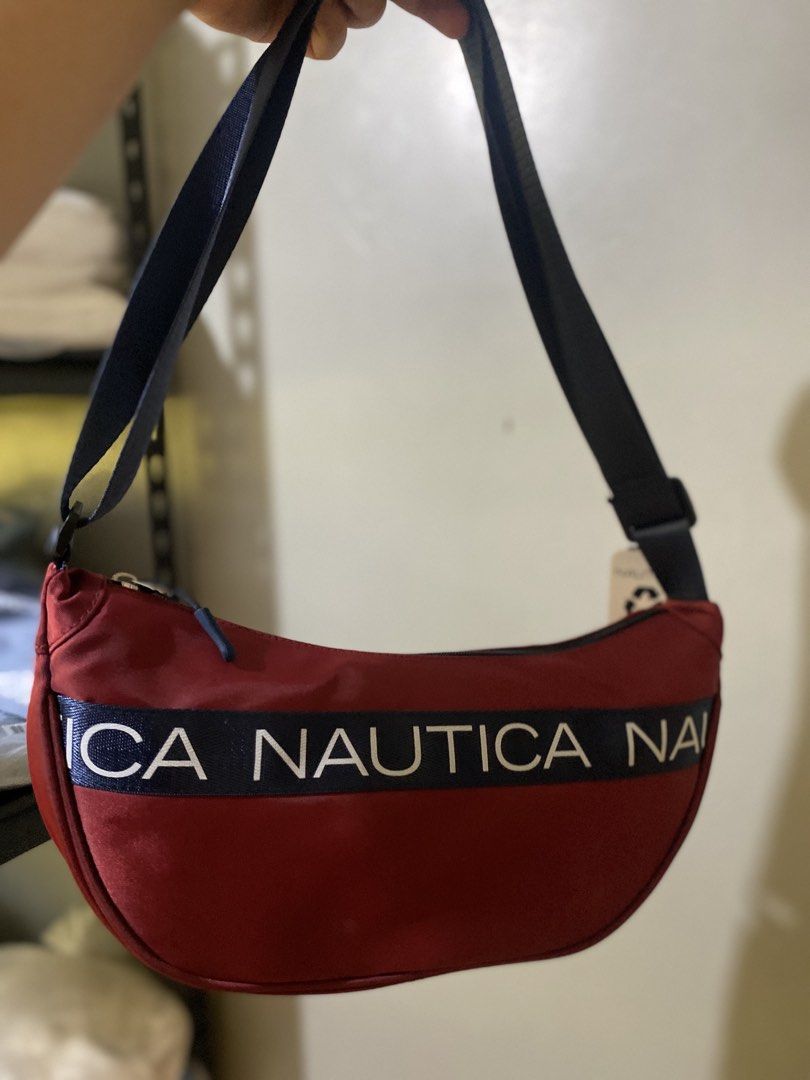 Nautica Red Crescent Shoulder Bag (Category: Shoulder Bags) located in Batangas. Submitted by lux_kimmy (Listing ID 1465989572, Image 1). Description: - Brand new with original tags and sealed in clear plastic - Striking red crescent design with dark blue strap and zipper closure - Features a bold Nautica logo tape printed across the front - Convenient exterior zipper pocket on the back - Adjustable strap for a customized, comfortable fit Authent