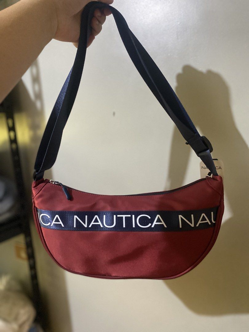 Nautica Red Crescent Shoulder Bag (Category: Shoulder Bags) located in Batangas. Submitted by lux_kimmy (Listing ID 1465989572, Image 2). Description: - Brand new with original tags and sealed in clear plastic - Striking red crescent design with dark blue strap and zipper closure - Features a bold Nautica logo tape printed across the front - Convenient exterior zipper pocket on the back - Adjustable strap for a customized, comfortable fit Authent
