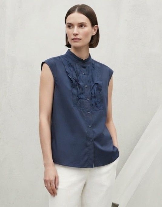 Navy Blue Sleeveless Ruffled High Collar linen Blouse (Category: Sleeveless) located in Donsol. Submitted by saksthriftavenuebyluckymaria8 (Listing ID 1466098034, Image 1). Description: - Color: Navy blue - Style: Sleeveless blouse with pleated front ruffles - Neckline: High mandarin collar with button-up closure - Fabric: Lightweight and comfortable - Versatility: Perfect for work or smart casual outings, easy to pair with trousers or skirts Che