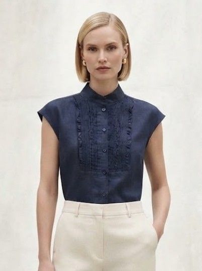 Navy Blue Sleeveless Ruffled High Collar linen Blouse (Category: Sleeveless) located in Donsol. Submitted by saksthriftavenuebyluckymaria8 (Listing ID 1466098034, Image 2). Description: - Color: Navy blue - Style: Sleeveless blouse with pleated front ruffles - Neckline: High mandarin collar with button-up closure - Fabric: Lightweight and comfortable - Versatility: Perfect for work or smart casual outings, easy to pair with trousers or skirts Che