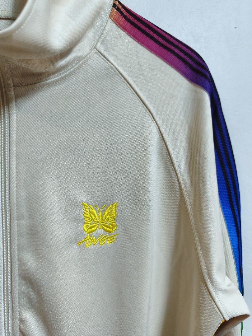 Needles x AWGE Track Jacket Off-White Rainbow (Category: Coats, Jackets and Outerwear) located in Taytay. Submitted by bunsoanglo096 (Listing ID 1466070145, Image 3). Description: W23 L29 cut size tag - Authentic Needles x AWGE collaborative track jacket - Color: Off-white base with colorful rainbow striped taping on sleeves - Features: Full zip closure, high collar, and secure side zip pockets - Branding: Yellow embroidered butterfly logo, AWGE 