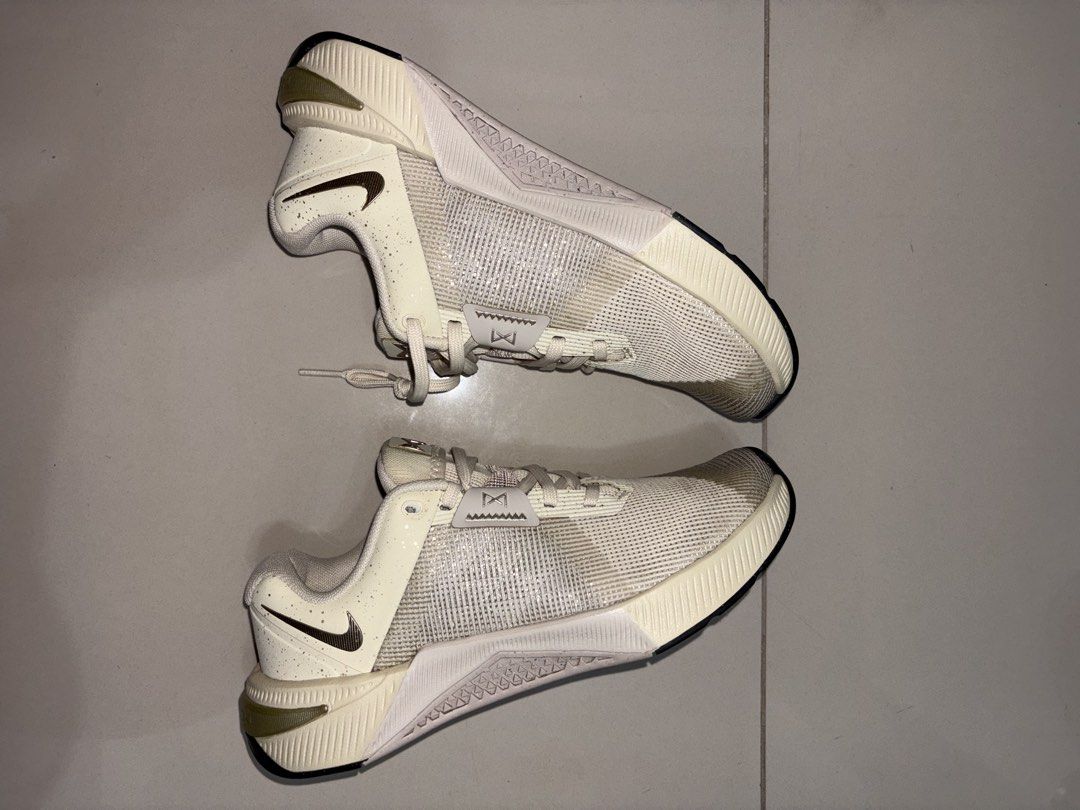 Nike Metcon Training Shoes (Category: Sneakers) located in Manila. Submitted by jonellefer78528 (Listing ID 1466008154, Image 2). Description: - Brand/Model: Nike Training Shoes - Color: Off-white and cream with metallic bronze swoosh and tongue logo - Upper: Breathable mesh with secure lace-up fastening and midfoot lockdown strap - Sole: Cushioned with a flat, stable base ideal for weightlifting and gym workouts - Condition: Uppers are still cle
